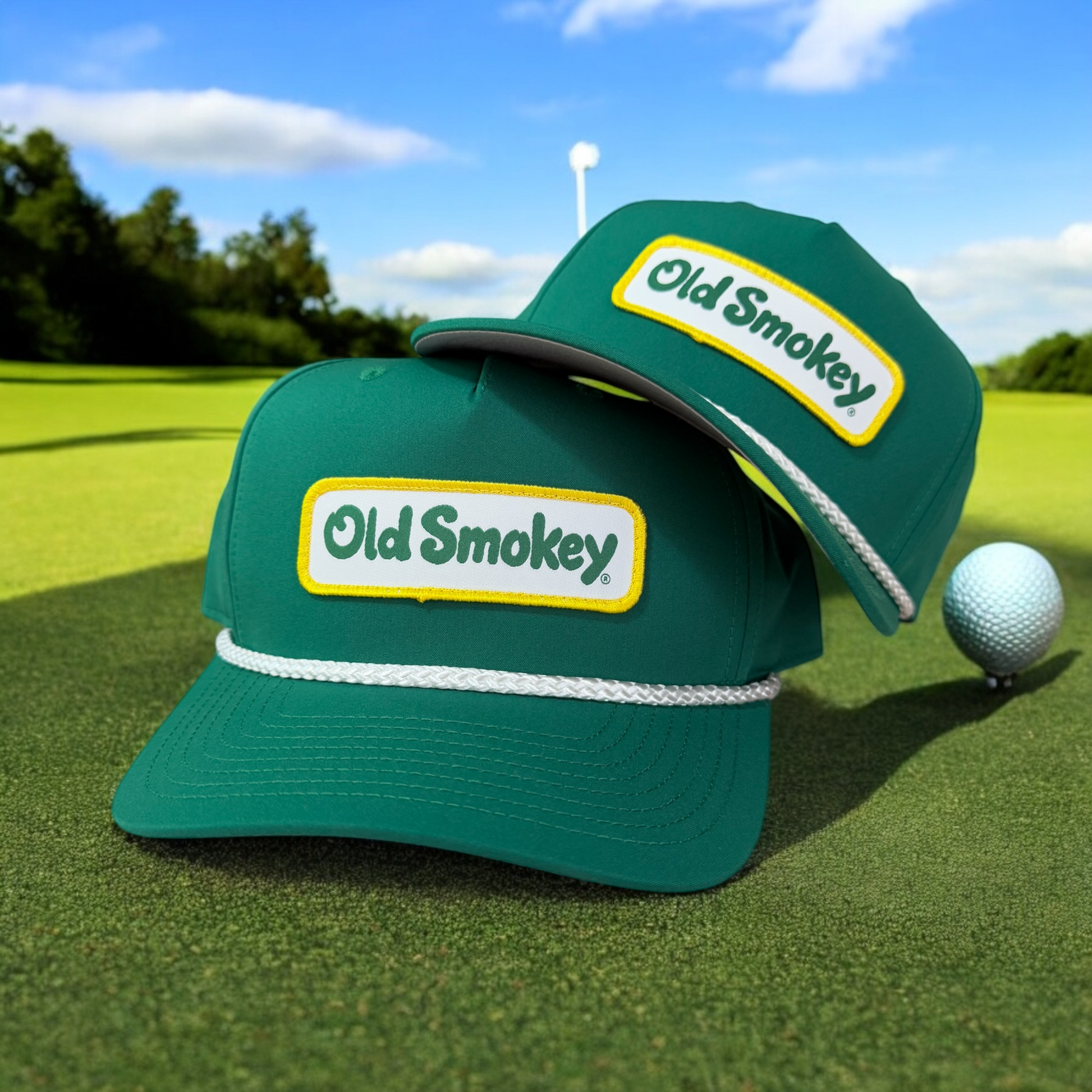 Two green Old Smokey hats laying on a golfcourse grass