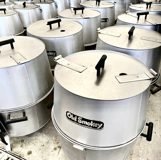 Multiple Old Smokey barbecue smokers lined up on a concrete floor.