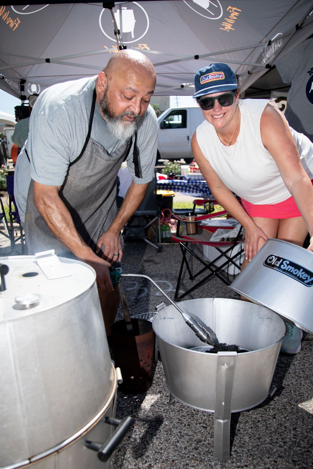 Two people cooking with an Old Smokey Charcoal Grill in street for a cookout event